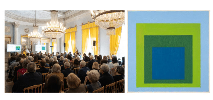 Pubblico seduto in una sala con grandi finestre e tende gialle a Villa e Collezione Panza durante un evento culturale del 2026.