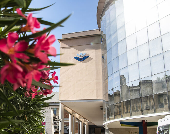 Vista esterna dell'Ospedale Pediatrico Bambino Gesù con piante e fiori in primo piano.