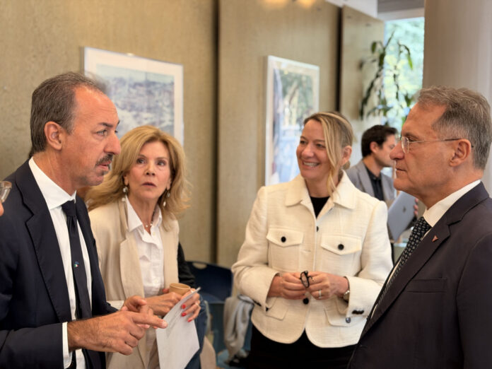 Persone in abiti formali conversano in una stanza durante un evento istituzionale, immagine di archivio.