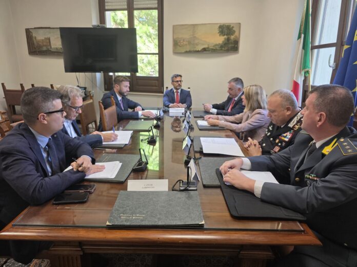 Incontro in Prefettura con ufficiali delle forze di polizia e amministratori seduti attorno a un tavolo durante una riunione.