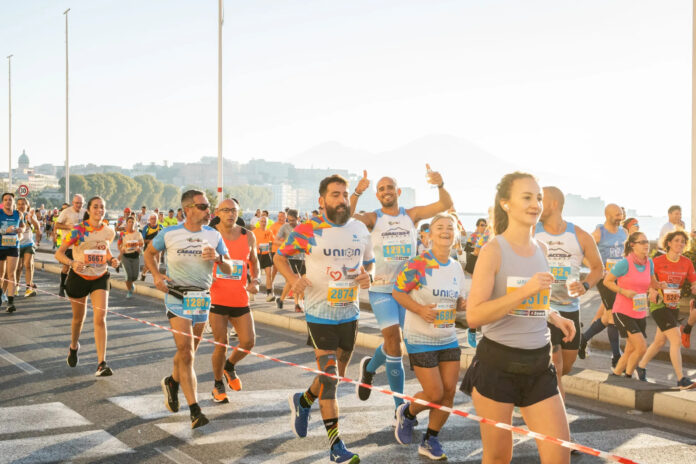 Partenza della corsa con molti atleti e pubblico presente, con uno striscione di partenza della Neapolis Marathon.