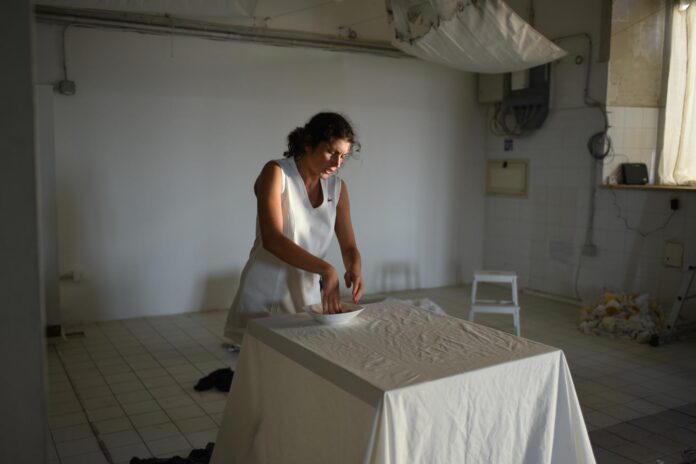 Attrice vestita di bianco in scena durante lo spettacolo teatrale tratto dal romanzo Uvaspina.