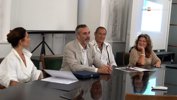 Foto della conferenza stampa con quattro persone sedute a un tavolo, tratto dal comunicato sulla manifestazione sportiva e artistica a Napoli.