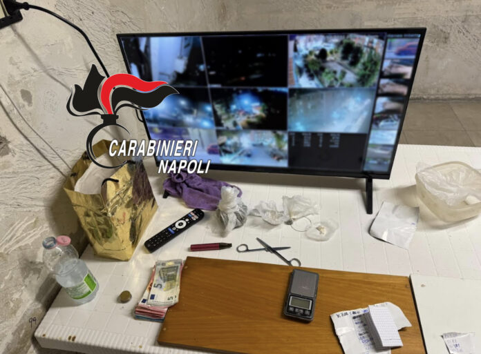 Monitor con immagini di sorveglianza e materiali sequestrati dai Carabinieri in un ambiente di Napoli.