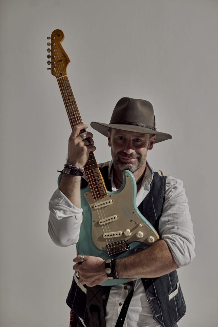 Vince May con chitarra elettrica in una fotografia promozionale per il brano 'Street of Heaven' e l'EP 'Peacefare'.