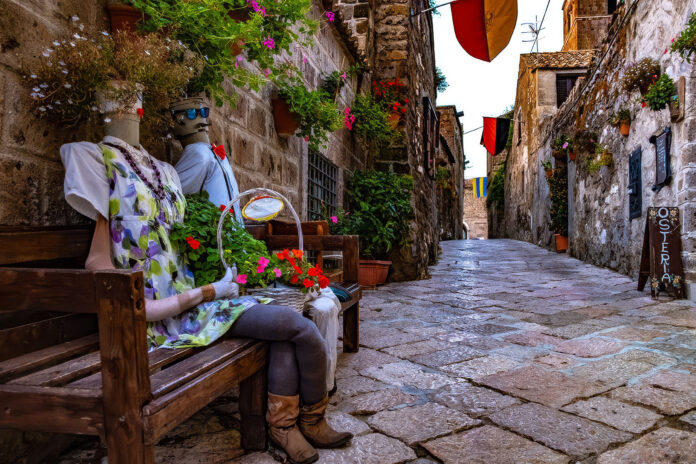 Borgo medievale di Casertavecchia con vicolo pedonale, panchine e decorazioni floreali.