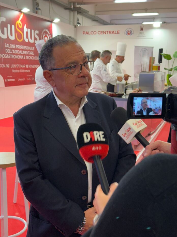 Intervista a Corrado Martinangelo durante evento Gustus con chef sullo sfondo