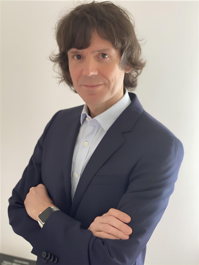 Ritratto di Umberto Zanatta, Senior Solutions Engineer di Acronis, con abito formale e braccia incrociate.