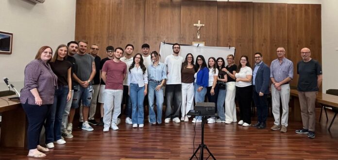 Gruppo di giovani volontari e rappresentanti istituzionali nella sala consiliare di Saracena, in posa per una fotografia di gruppo.