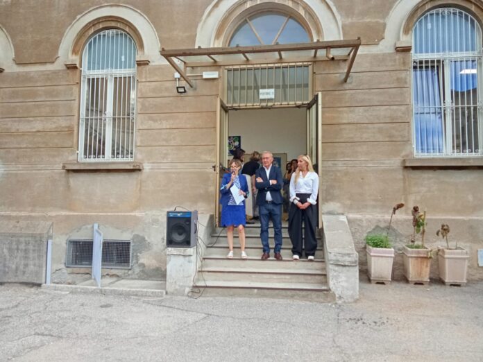 Il Sindaco Andrea Pellicini e l'Assessore all'Istruzione Roberta Longhi in piedi davanti all'entrata di una scuola durante il primo giorno di scuola.