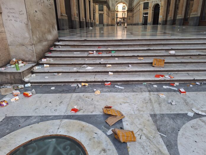 Gradini dell'ingresso della Galleria Umberto I con rifiuti sparsi e degrado visibile.