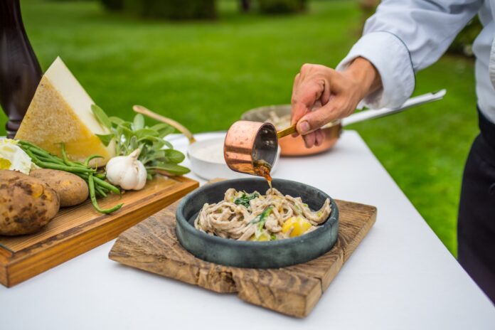 Preparazione del piatto tipico valtellinese con formaggi e ingredienti sulla tavola
