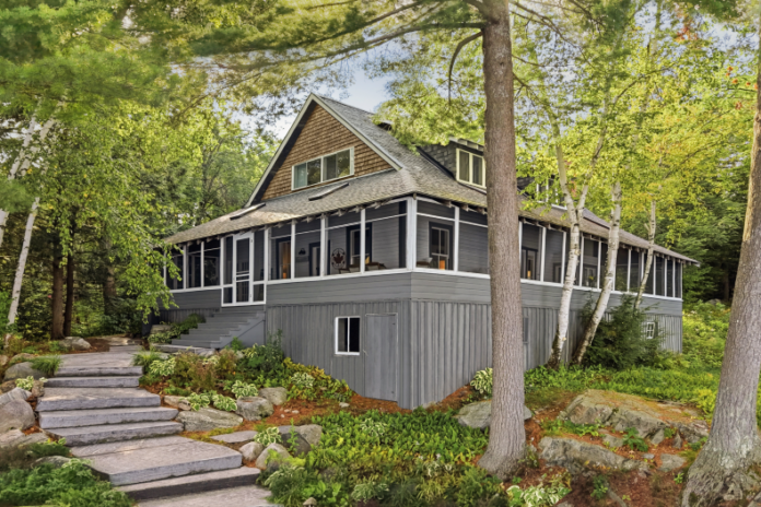 Veduta esterna del Gordon Bay Cottage circondato da alberi e vegetazione rigogliosa, con un percorso di pietre che conduce all'ingresso della casa.