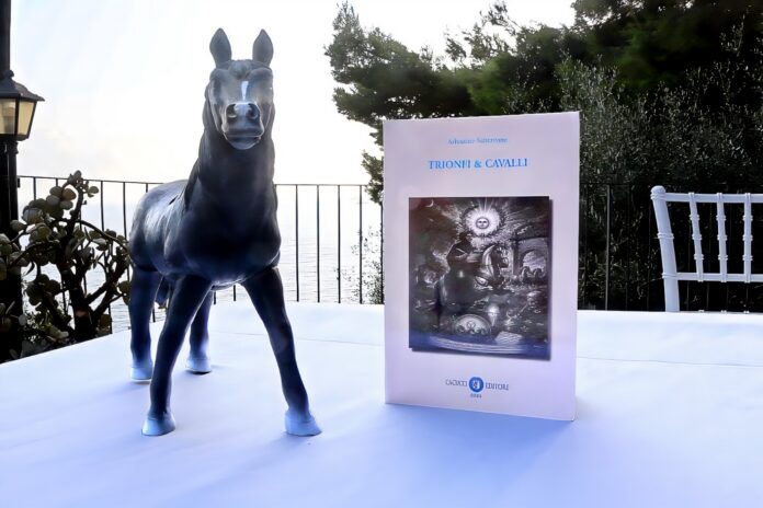 Il libro “Trionfi & Cavalli” accanto a una statua di cavallo, sullo sfondo natura e mare, in una cornice all'aperto.