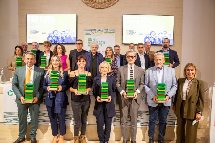 Foto di gruppo con persone che tengono premi verdi e neri durante una cerimonia di premiazione.