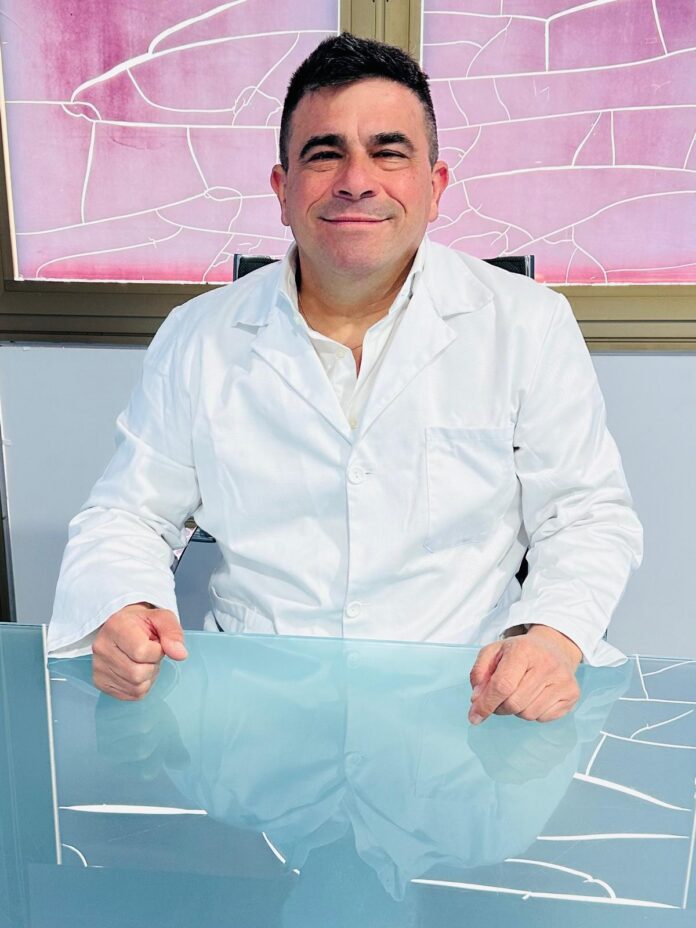 Ritratto del professor Mario Polichetti in camice bianco seduto a un tavolo.