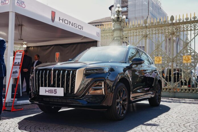 SUV Hongqi HS3 grigio esposto all'aperto con stand del marchio Hongqi e cancelli storici sullo sfondo, Salone Auto Torino.