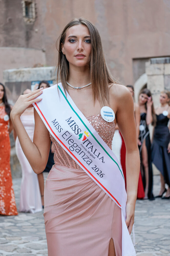 Francesca Longobardi con la fascia di Miss Eleganza 2026 posa durante la cerimonia di Miss Italia 2026 in abito elegante rosa pallido.