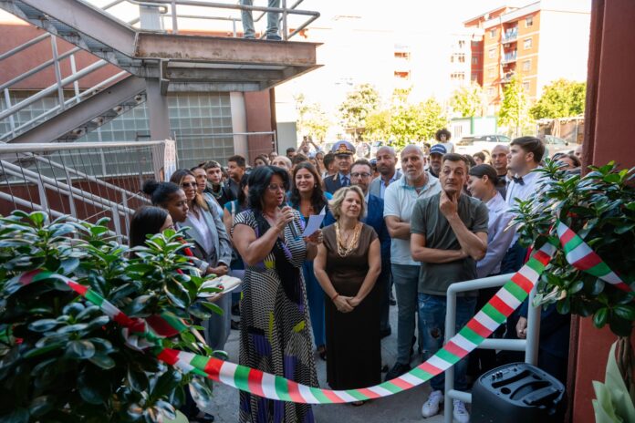 Cerimonia di inaugurazione con gruppo di persone all'aperto e nastro tricolore in primo piano.