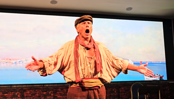 Attori sul palco in costumi tradizionali durante lo spettacolo 'Note di Incanto Napoletano' con scena e schermo digitale sullo sfondo.