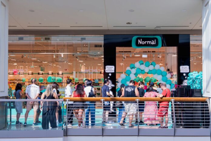 Persone in fila davanti a un negozio con palloncini all'interno di un centro commerciale.