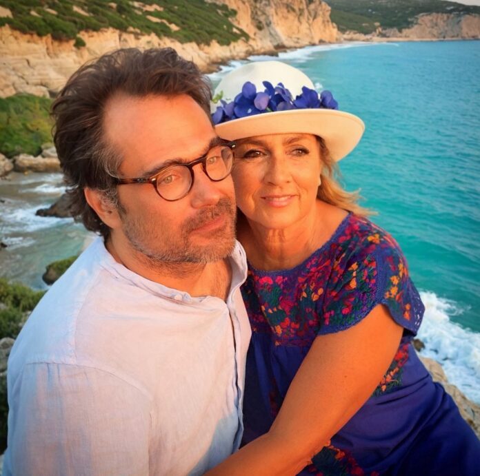 Romina Power con un accompagnatore in un'immagine fornita dall'ufficio stampa, sullo sfondo un paesaggio costiero.