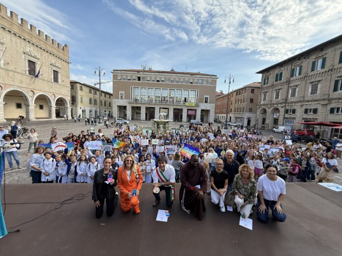 Assemblea di bambini e adulti in piazza del Popolo a Pesaro durante evento Lampada della Pace di San Francesco.
