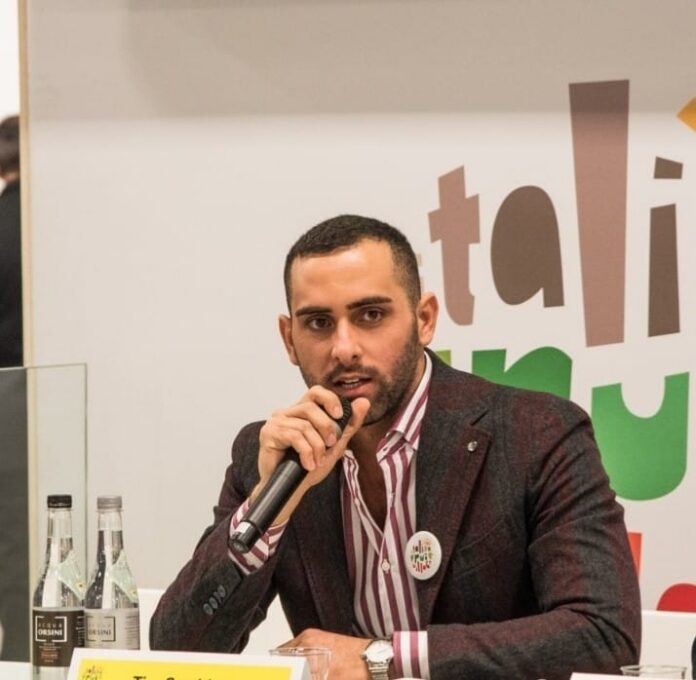 Uomo che parla al microfono in un incontro pubblico sulla pianificazione urbanistica.
