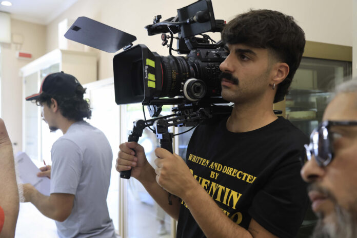 Studente della Scuola di Cinema Pigrecoemme con telecamera professionale su set cinematografico