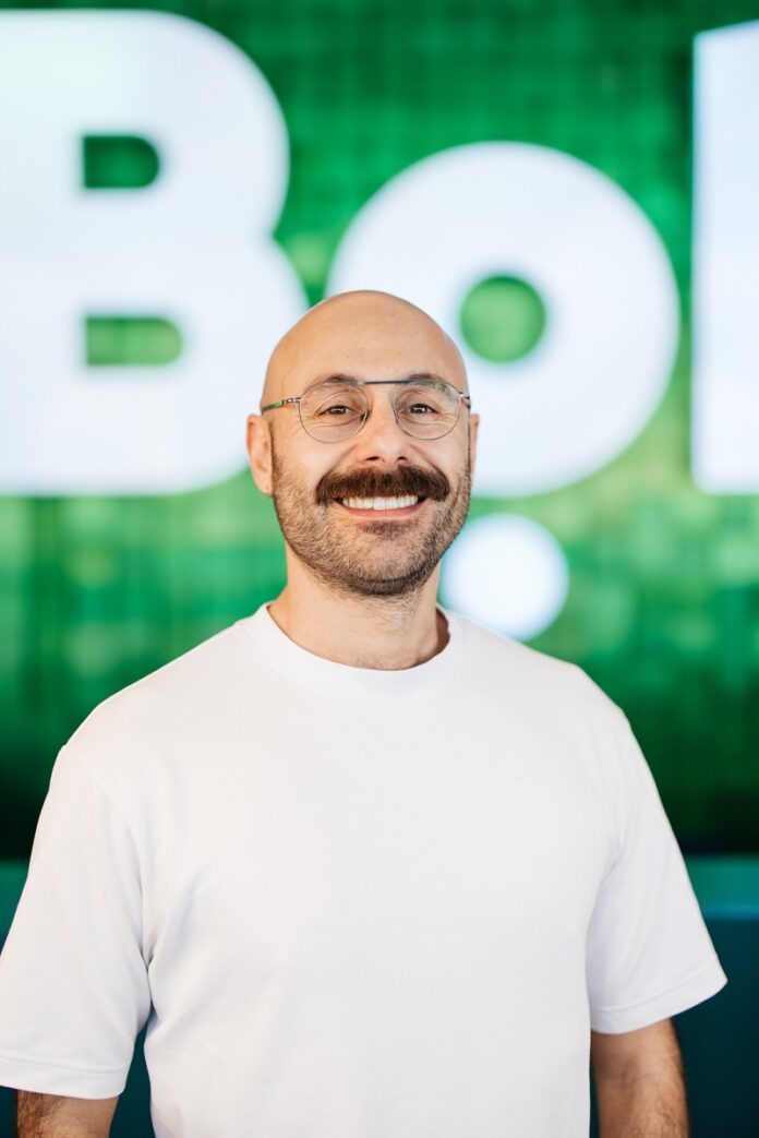 Una persona sorridente davanti al logo di Bolt su sfondo verde.
