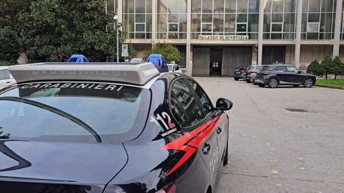 Auto dei Carabinieri parcheggiata davanti a un edificio giudiziario.