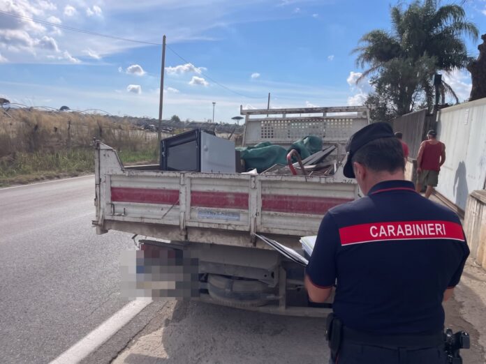 Carabiniere in campo durante un controllo stradale su un veicolo carico di materiali.