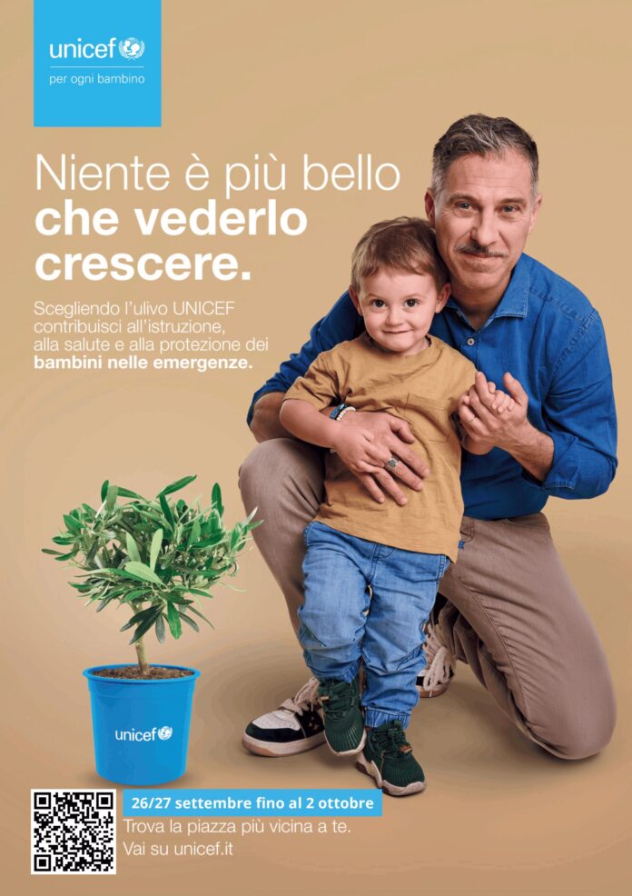 Uomo e bambino posano con una piantina di ulivo in vaso con logo UNICEF, immagine promozionale della campagna UNICEF.