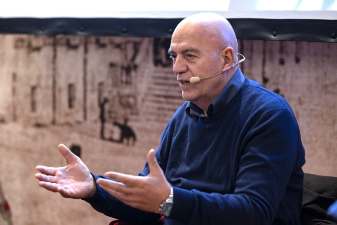 Marco Rizzo mentre parla con microfono a archetto e gesticola con le mani