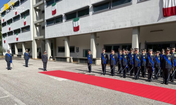 Cerimonia ufficiale della Guardia di Finanza con militari in uniforme schierati e tappeto rosso all'esterno di un edificio