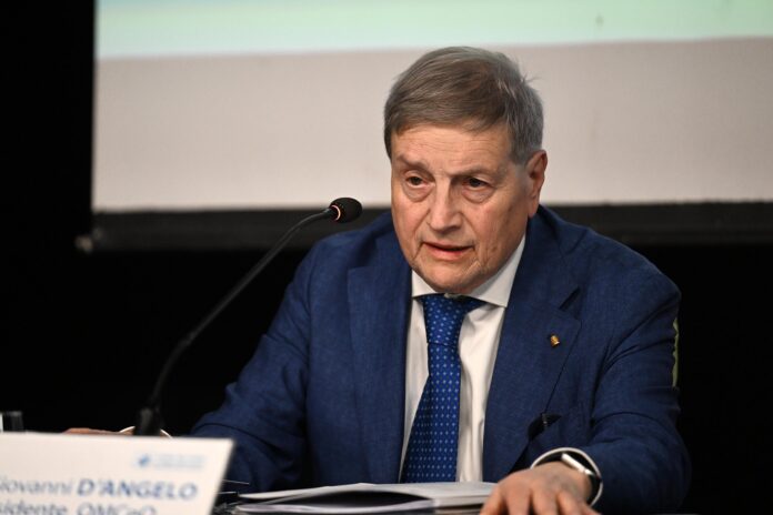 Giovanni D'Angelo in abito blu che parla davanti a un microfono