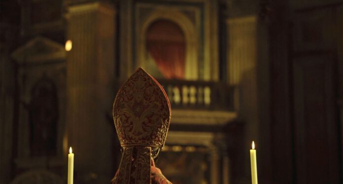 Locandina del film 'O SANG. IL MIRACOLO DI SAN GENNARO' con un uomo che alza una reliquia sacra in mezzo a una folla durante una processione.