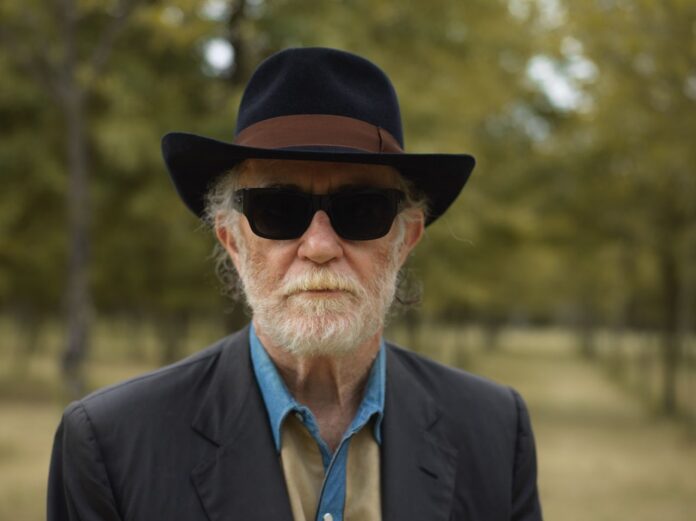 Francesco De Gregori con cappello e occhiali da sole in un ambiente naturale, immagine di archivio.
