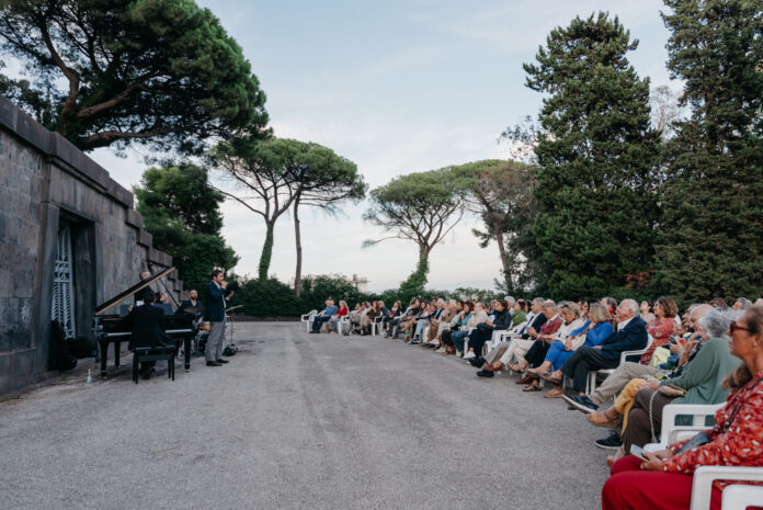 Concerto all'aperto con pubblico seduto e musicisti a Napoli durante festival Vespero Napoletano
