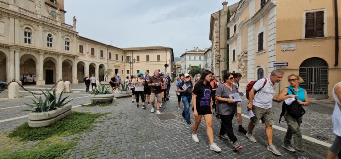 Gruppo di persone in cammino lungo una strada di città durante il pellegrinaggio diocesano a piedi