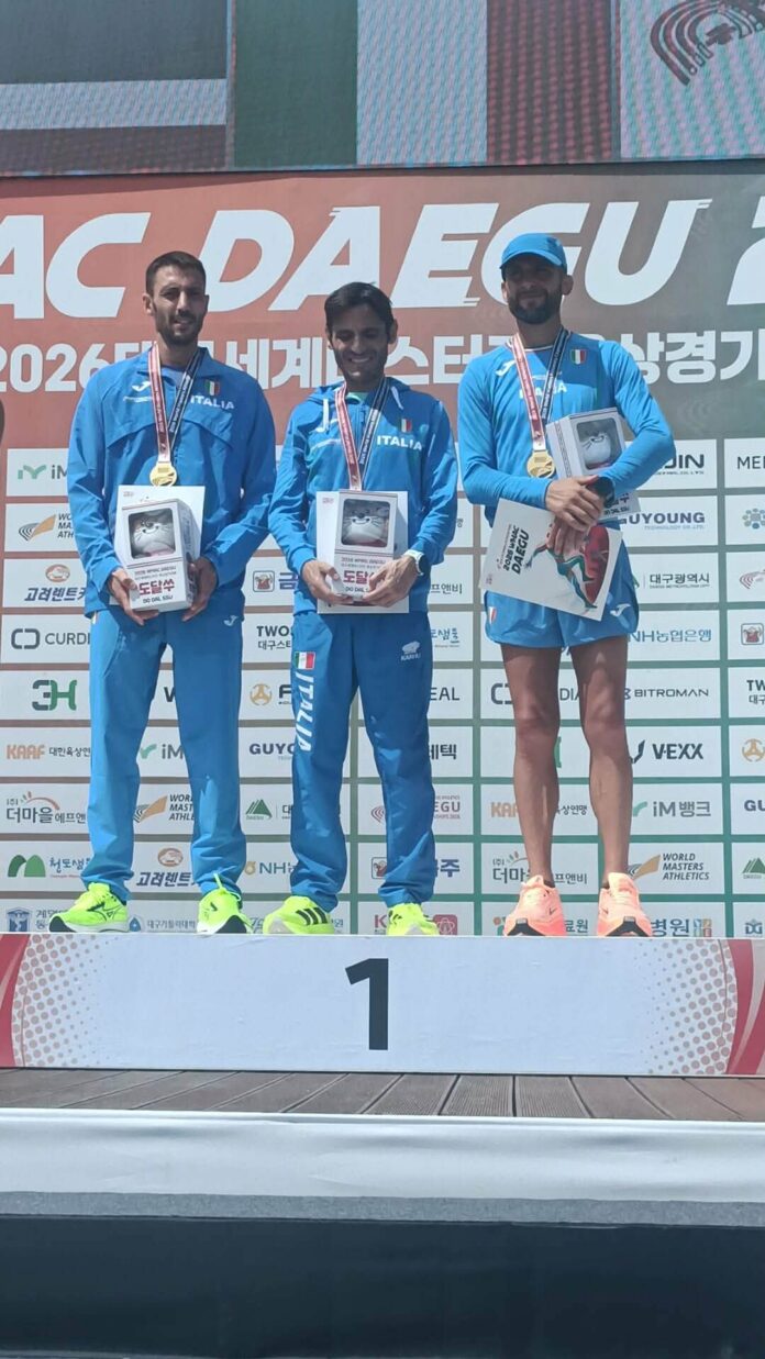 Atleta Stefano Tarì con bandiera italiana e tabellone risultati a Daegu 2026
