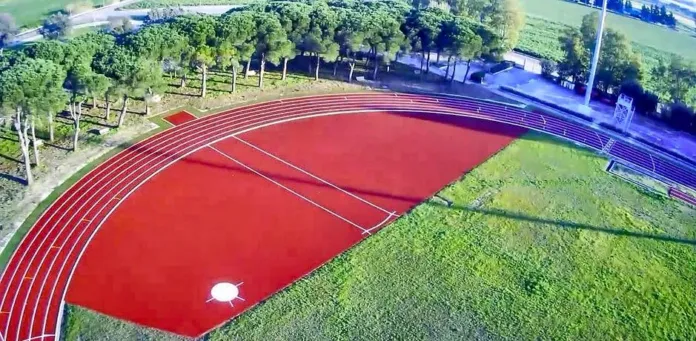Vista dall’alto di una pista di atletica rossa circondata da un’area verde.