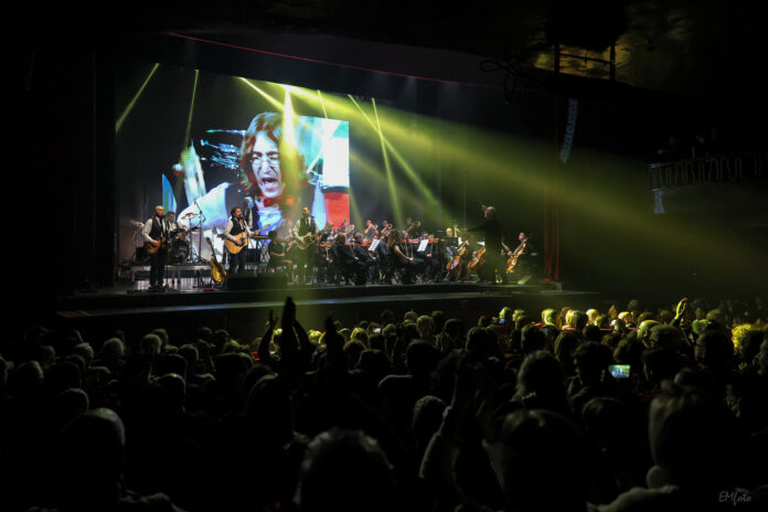 Concerto con band e orchestra dal vivo sul palco, luminarie e pubblico in sala per lo spettacolo A Beatles' Orchestra: Lennon & McCartney.