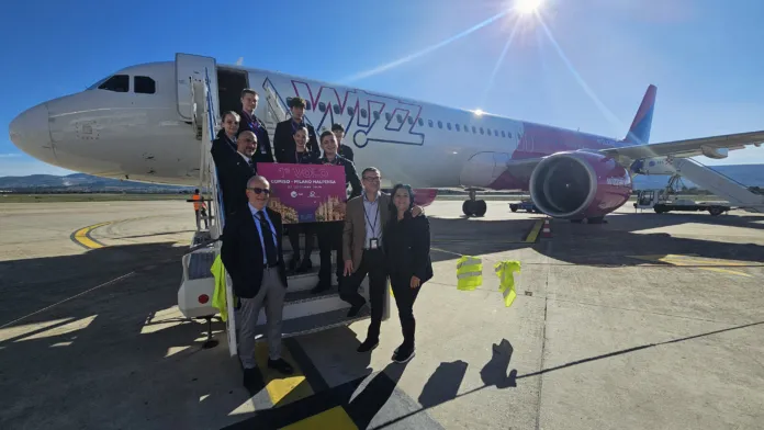 Un gruppo di persone posa davanti a un aereo Wizz Air fermo sulla pista.