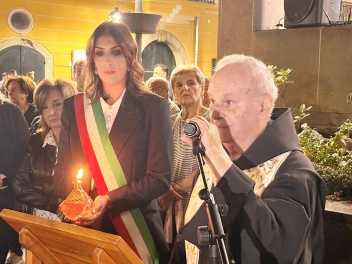 Foto di gruppo della comunità in processione con la statua di San Francesco durante l'evento della Lampada della Pace a Baronissi di sera.