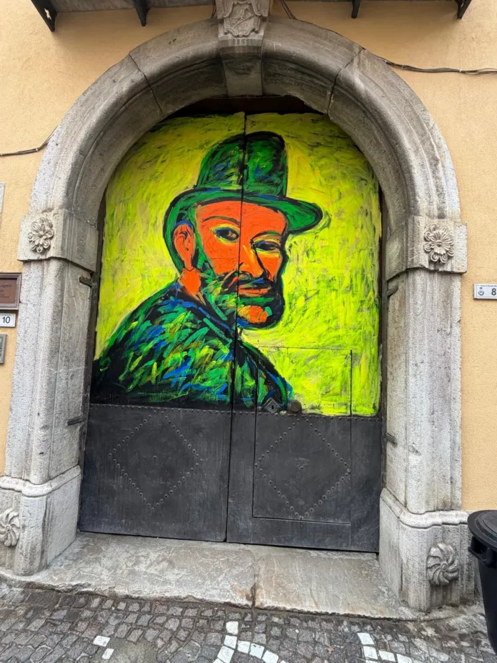 Un portone scuro inserito in un arco di pietra è dipinto con un grande ritratto dai colori vivaci.