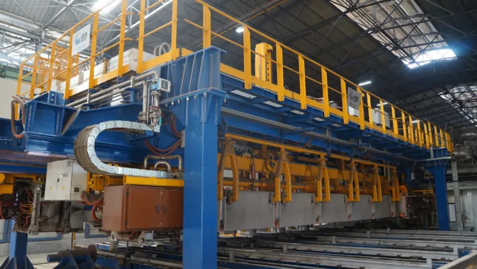 Impianto industriale con macchinari blu e arancioni, passerelle e strutture metalliche.