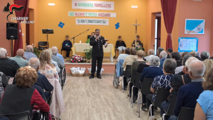 Incontro tra carabinieri e anziani in una sala durante la Festa dei Nonni a Torella dei Lombardi con interventi di prevenzione truffe.