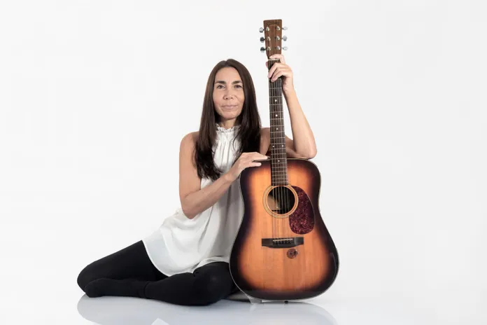 Cantautrice seduta con chitarra, immagine di presentazione del libro