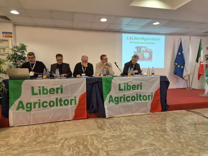 Fotografia di un meeting o conferenza di agricoltori con i rappresentanti seduti dietro un tavolo, presenti bandiere italiane ed europee, tratta da materiale illustrativo.